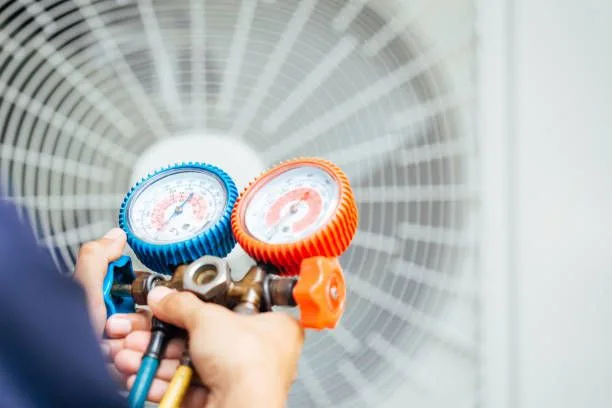 Technician servicing an HVAC unit with pressure gauges